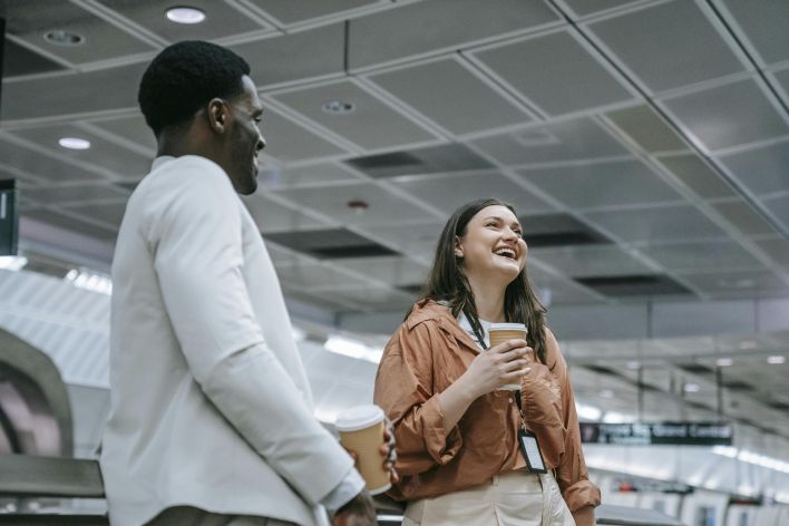 A joyful couple sharing a moment indoors, holding coffee cups and smiling warmly.