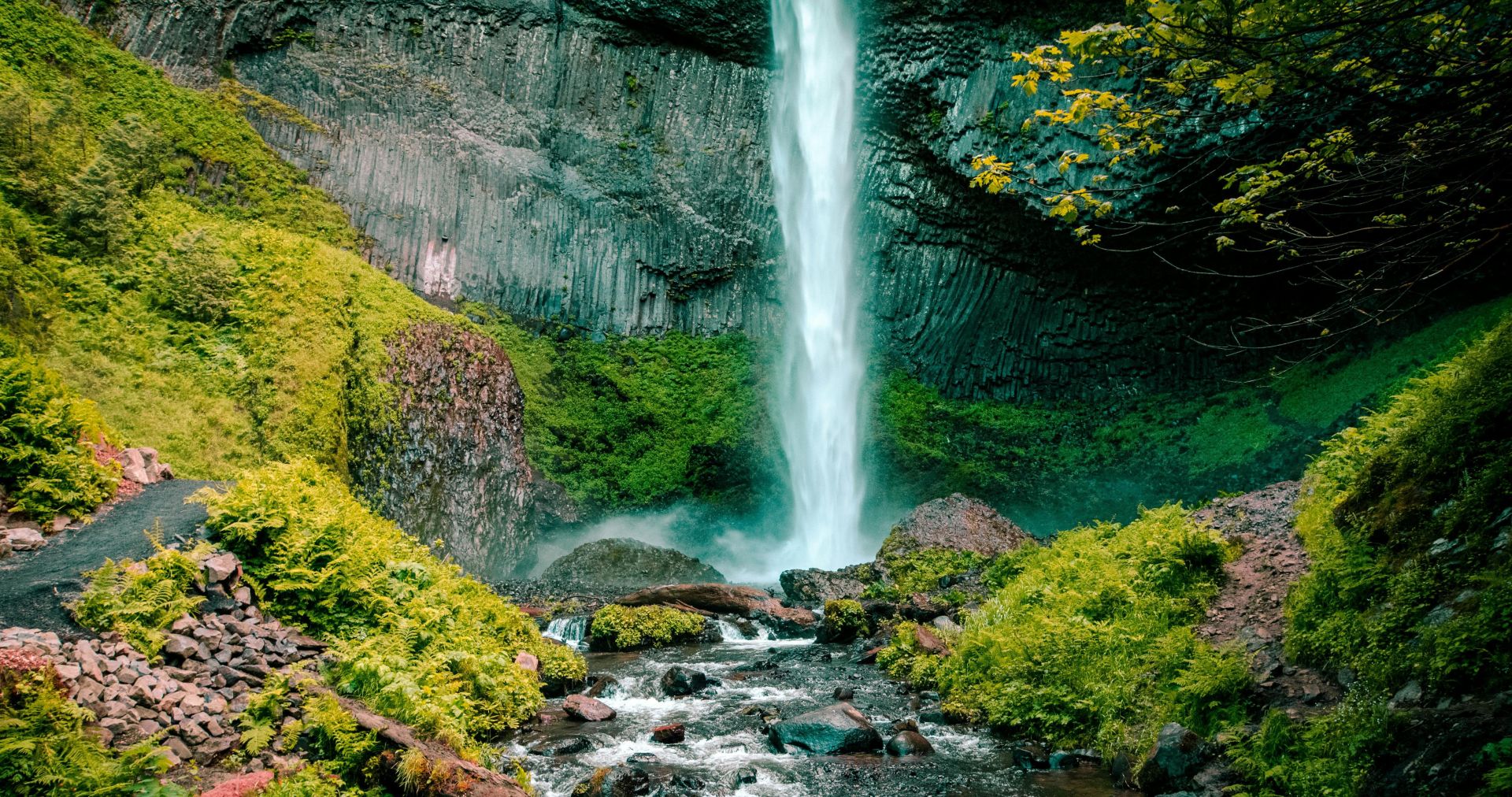 Majestic waterfall cascading down rocky cliff surrounded by vibrant greenery in a serene outdoor location.