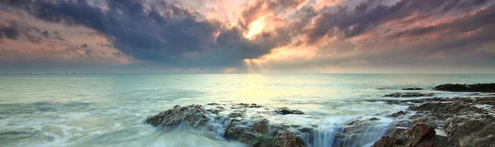 Beautiful sunrise over ocean rocks with waves crashing, capturing the serenity and power of nature.