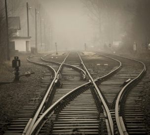 Moody foggy railway tracks in a misty landscape, evoking travel and mystery.